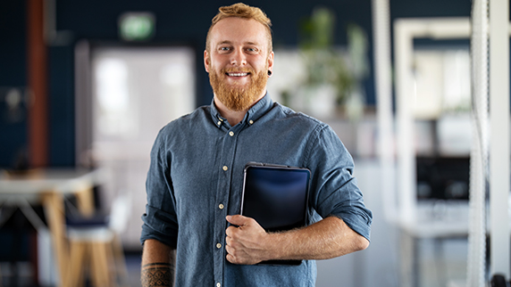 Man holding laptop and smiling at camera